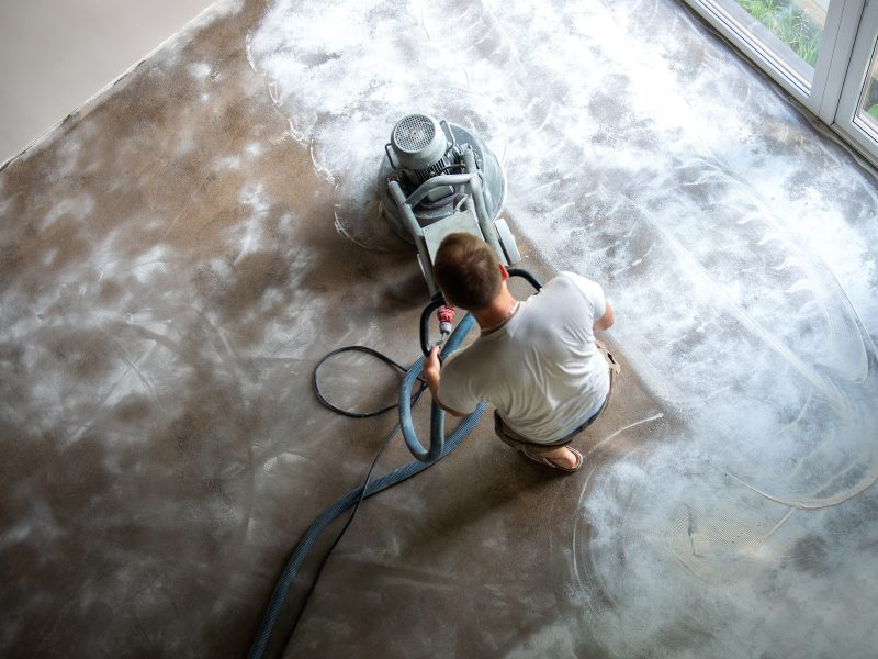 Builder workers working with concrete floor grinding machine, concrete floor repair