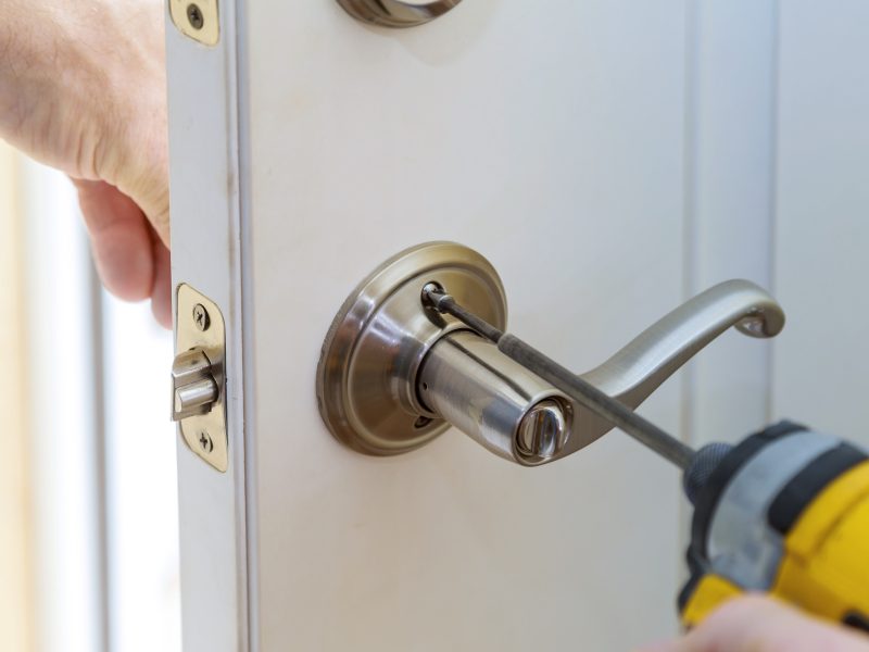 handyman repair the door lock in the worker's hands installing new door locker