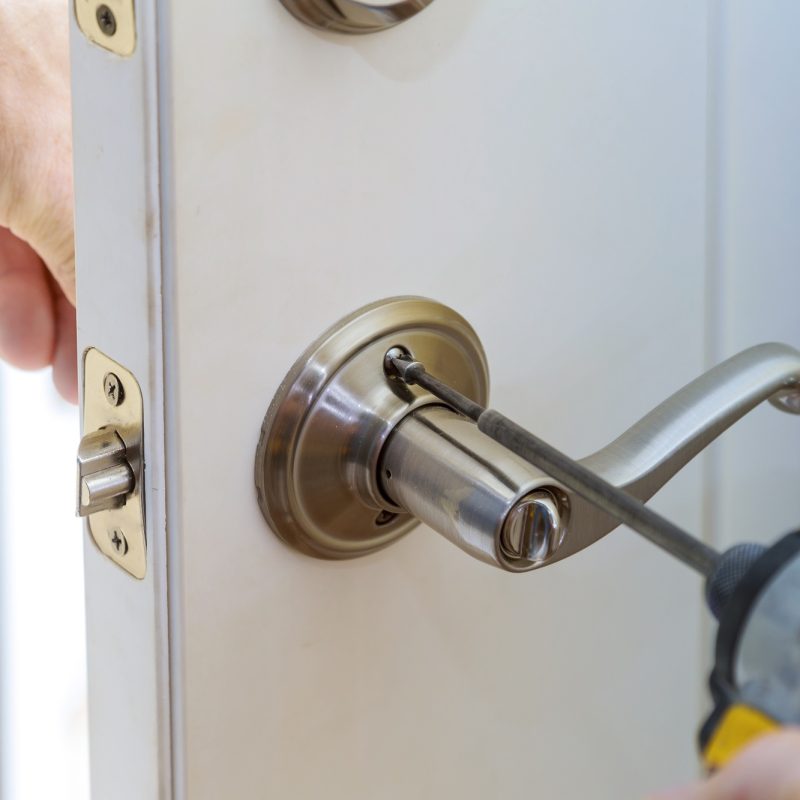 handyman repair the door lock in the worker’s hands installing new door locker handyman repair the door lock in the worker's hands installing new door locker