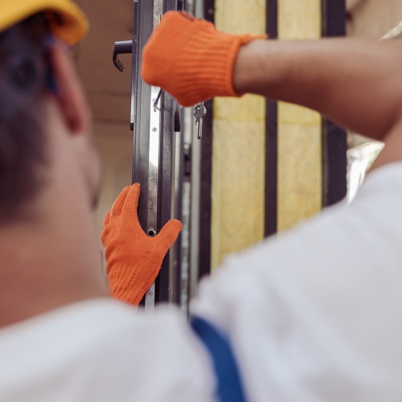 Male worker repairing door in building under construction Male worker repairing door in building under construction
