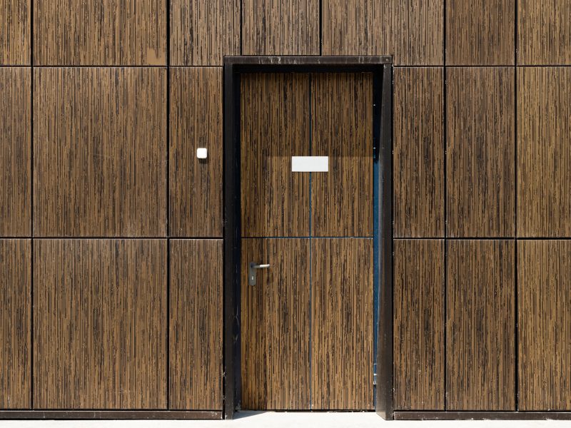Tiled brown wall with built-in camouflaged door, front view. Copyspace on door.