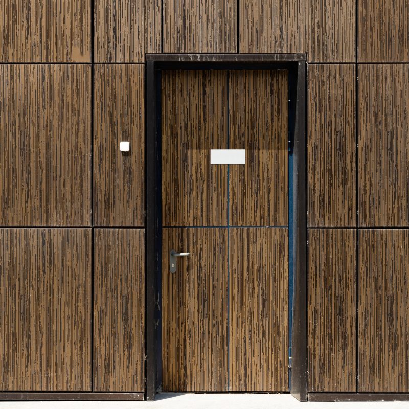 Tiled brown wall with built-in camouflaged door, front view. Copyspace on door. Tiled brown wall with built-in camouflaged door, front view. Copyspace on door.