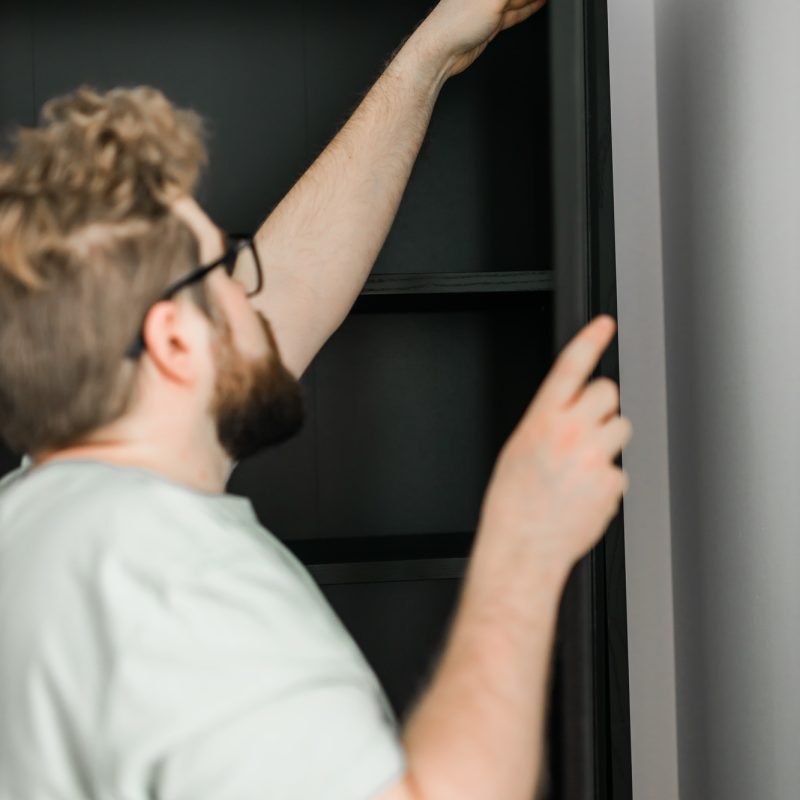 Young attractive man assembles furniture – handwerker and interior objects concept Young attractive man assembles furniture - handwerker and interior objects concept