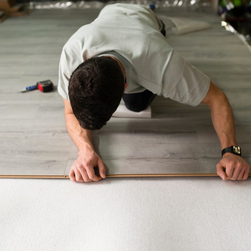 Young man placing a laminate floor Young man placing a laminate floor